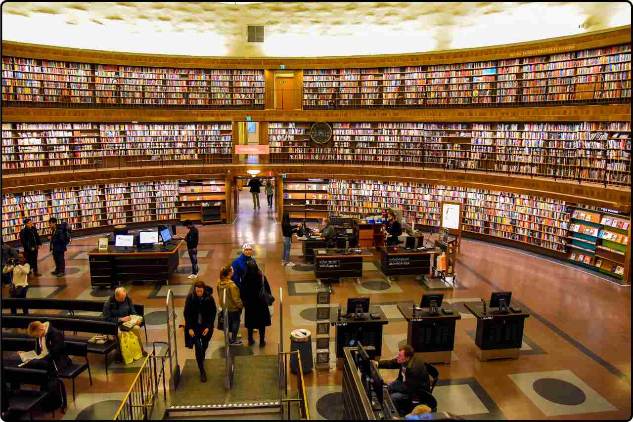 People in a public library surrounded by shelves of literature, faces not visible